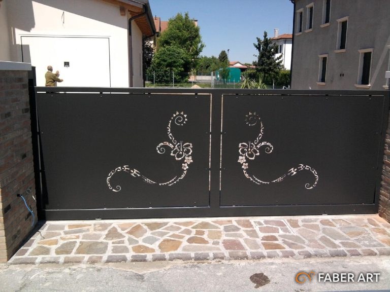 Cancello scorrevole in ferro nero con pannelli pieni decorati con motivi floreali sagomati.