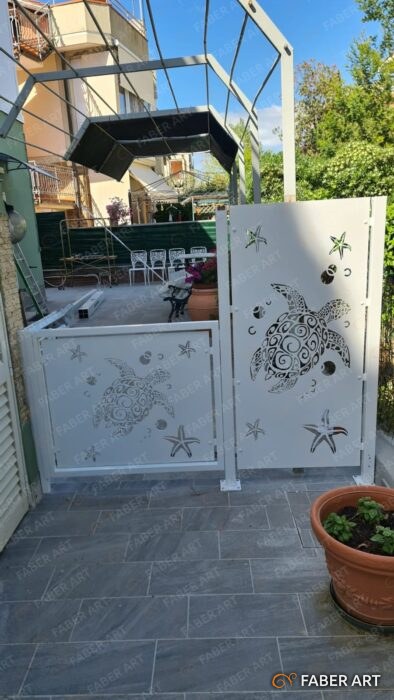 Pannelli e cancelletto in ferro bianco con decori marini intagliati in un terrazzo.
