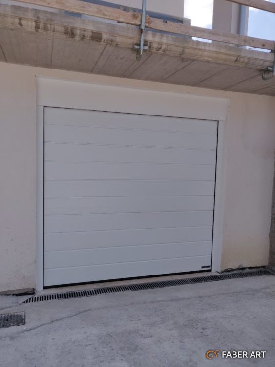 Portone sezionale motorizzato di colore bianco installato all ingressso di un garage