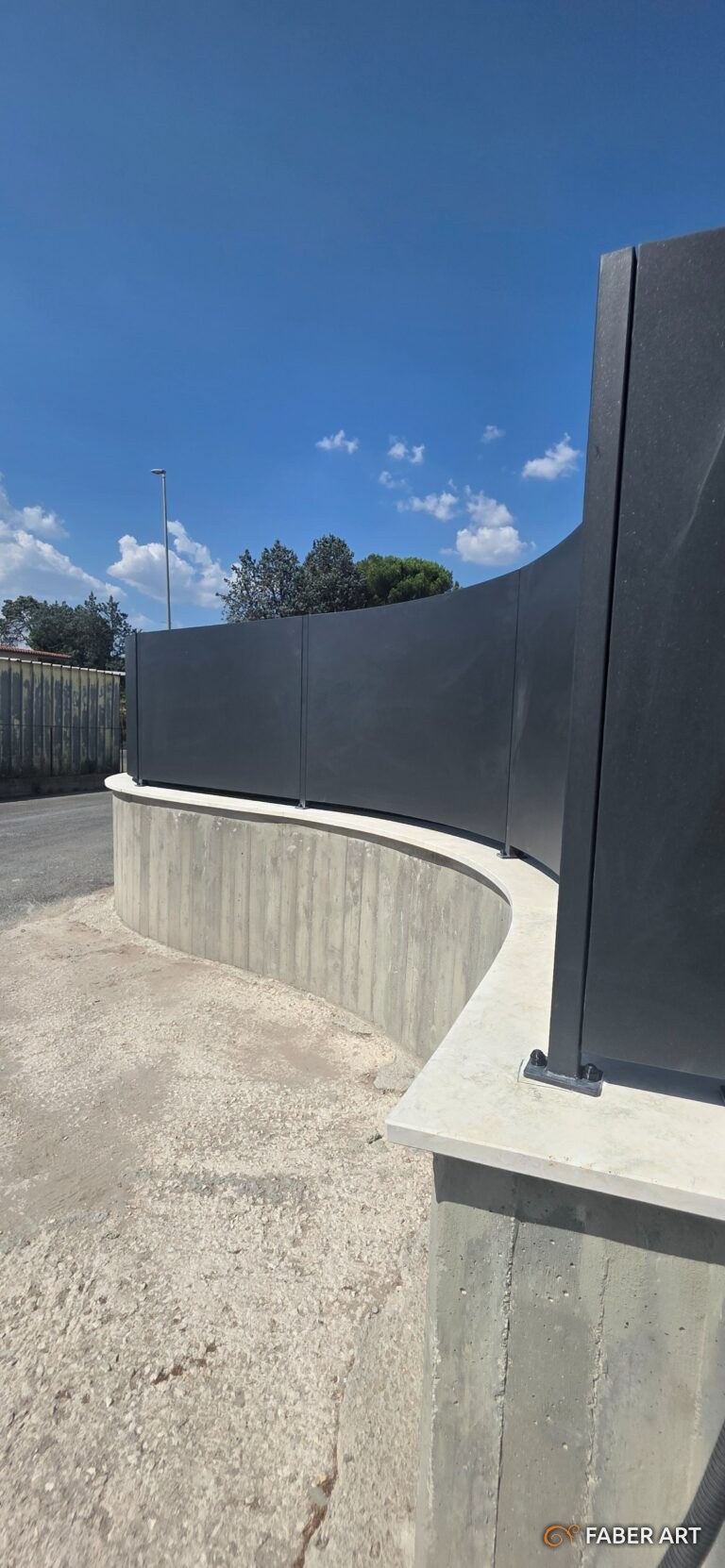 Recinzione metallica curva con pannelli oscuranti neri montata su muro di cemento