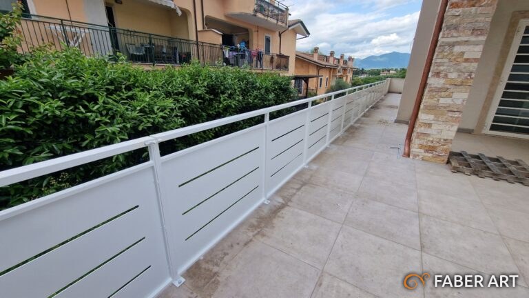 Ringhiera moderna bianca in metallo con pannelli orizzontali fessurati installata su un terrazzo.